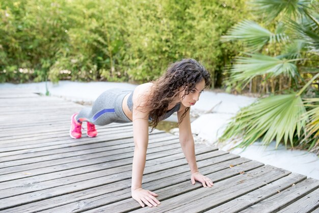 Hermosa mujer deportiva haciendo tablones en el Parque