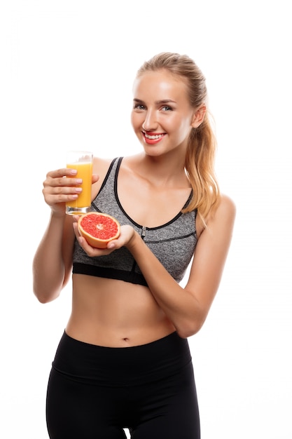 Hermosa mujer deportiva con pomelo y jugo