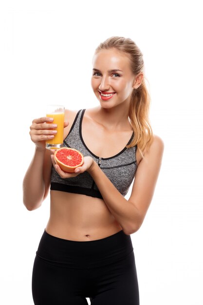 Hermosa mujer deportiva con pomelo y jugo