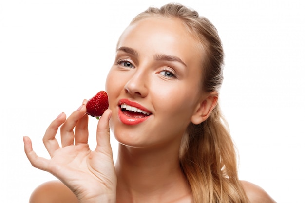 Hermosa mujer deportiva posando, comiendo fresa