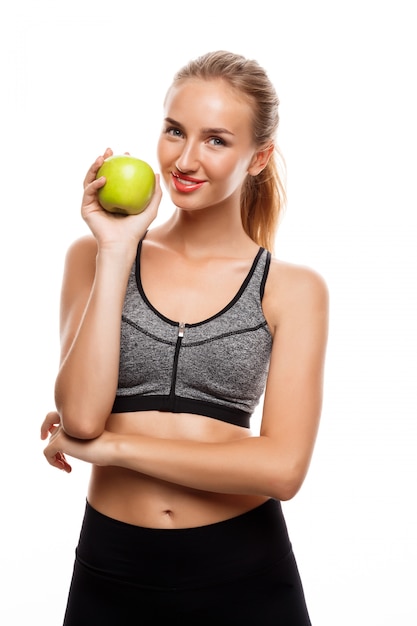 Hermosa mujer deportiva posando, sosteniendo apple