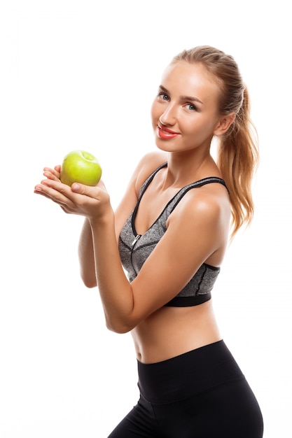 Hermosa mujer deportiva posando, sosteniendo apple