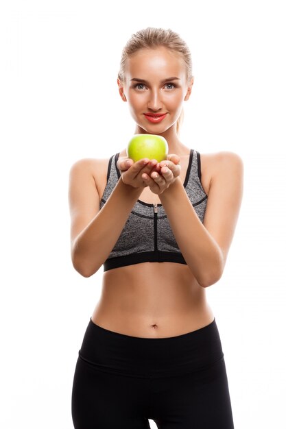 Hermosa mujer deportiva posando, sosteniendo apple