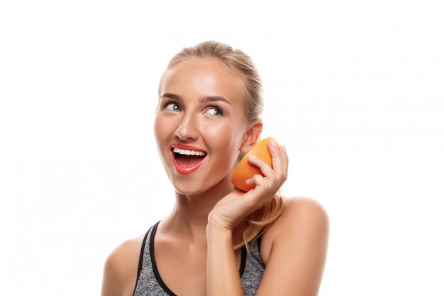 Hermosa mujer deportiva posando, sosteniendo pomelo