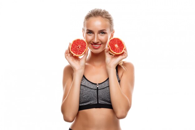 Hermosa mujer deportiva posando, sosteniendo pomelo