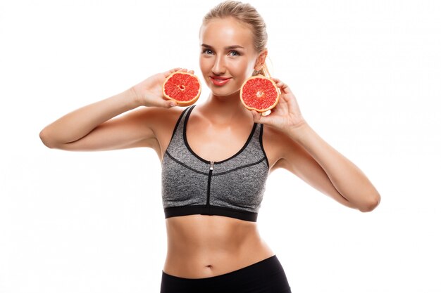 Hermosa mujer deportiva posando, sosteniendo pomelo