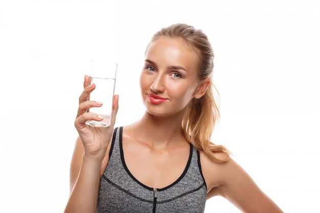 Hermosa mujer deportiva posando, sosteniendo un vaso de agua