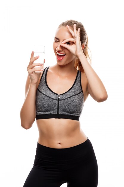 Hermosa mujer deportiva posando, sosteniendo un vaso de agua