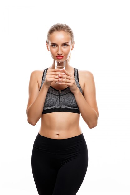 Hermosa mujer deportiva posando, sosteniendo un vaso de agua