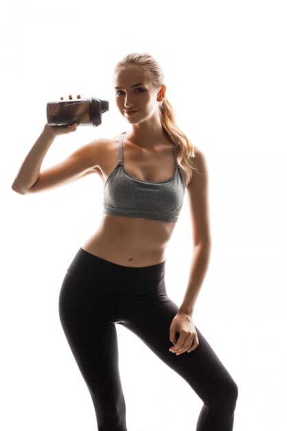 Hermosa mujer deportiva sosteniendo la botella, posando