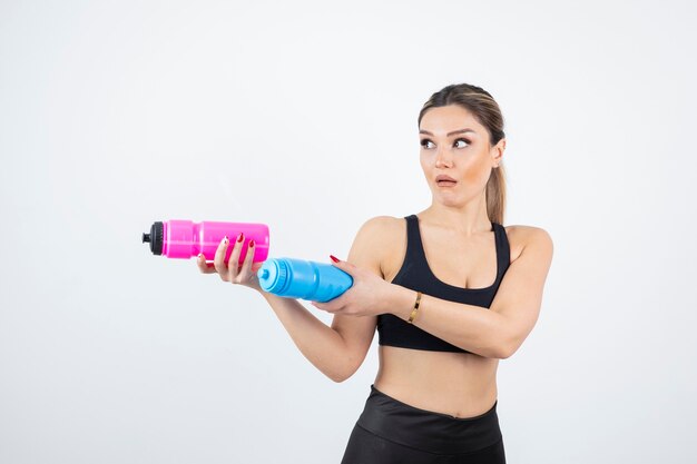 Hermosa mujer deportiva sosteniendo botellas con agua en blanco