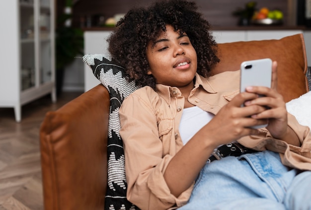 Foto gratuita hermosa mujer descansando en el sofá y mirando por teléfono