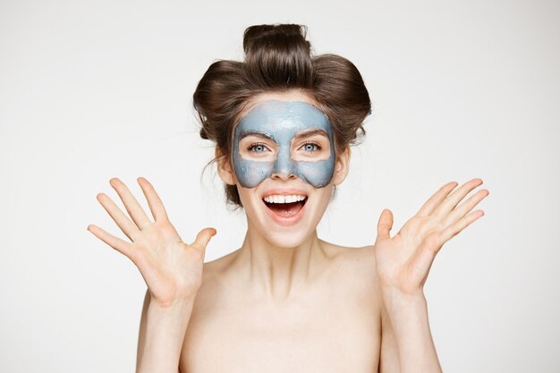 Hermosa mujer desnuda sorprendida en Rizadores para el cabello y máscara facial sonriendo. Boca abierta Belleza, salud, cosmetología y cuidado de la piel.