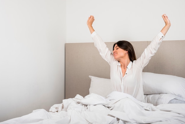 Hermosa mujer despertándose en su cama en el dormitorio.