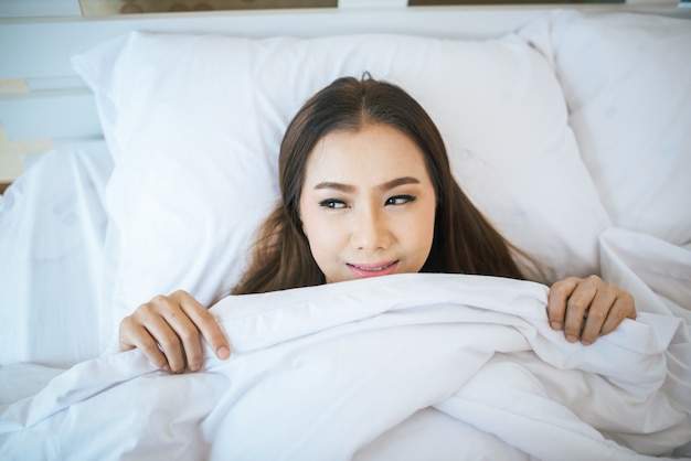 Hermosa mujer despertándose en su cama, perezosa por la mañana.