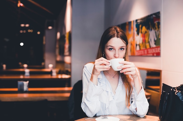 Hermosa mujer disfrutando de bebida en café