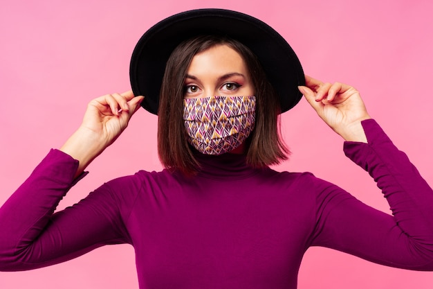 Hermosa mujer con elegante mascarilla protectora. Sombrero negro