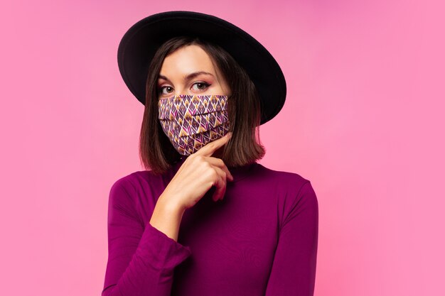 Hermosa mujer con elegante mascarilla protectora. Sombrero negro