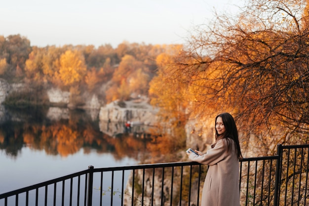 Hermosa mujer elegante de pie en un parque en otoño