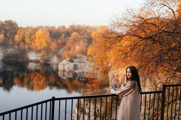 Hermosa mujer elegante de pie en un parque en otoño