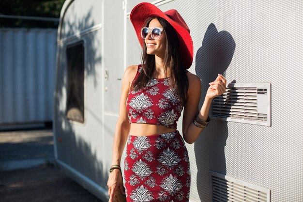 Hermosa mujer elegante posando contra el remolque plateado en traje de estilo tropical