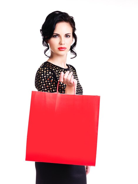 Foto gratuita hermosa mujer elegante en vestido negro con bolsa roja aislada en una pared blanca.