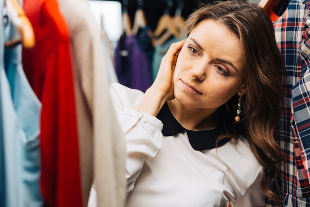 Hermosa mujer elegir traje en tienda