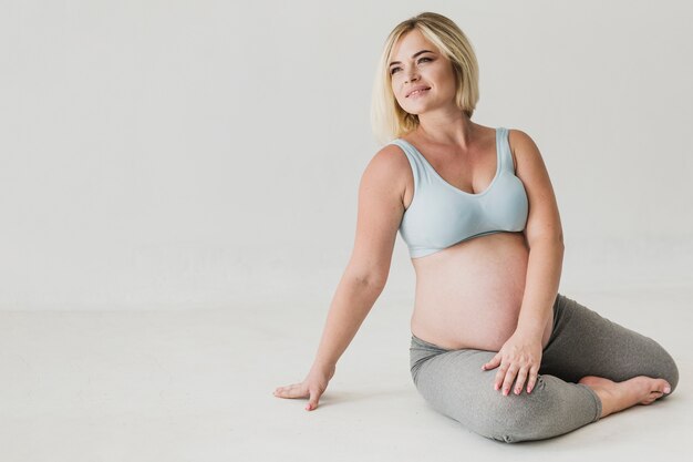 Hermosa mujer embarazada sentada en el piso con espacio de copia
