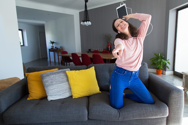 Hermosa mujer escuchando música y bailando en el sofá