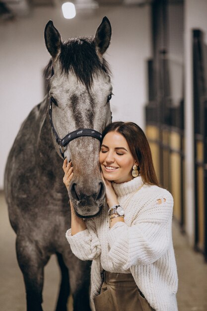 Hermosa mujer en un establo con caballo