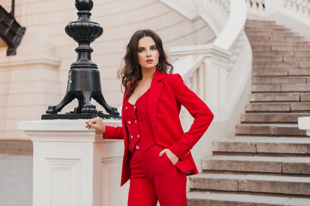 Hermosa mujer de estilo de negocios rico sexy en traje rojo caminando en la calle de la ciudad, tendencia de moda primavera verano