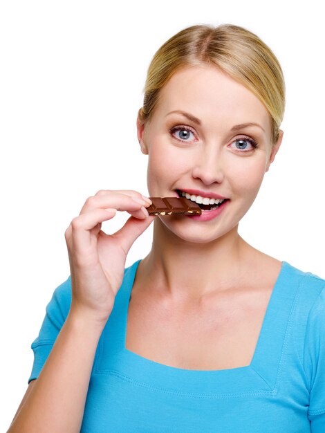 Hermosa mujer feliz come una rebanada de chocolate dulce - aislado en blanco