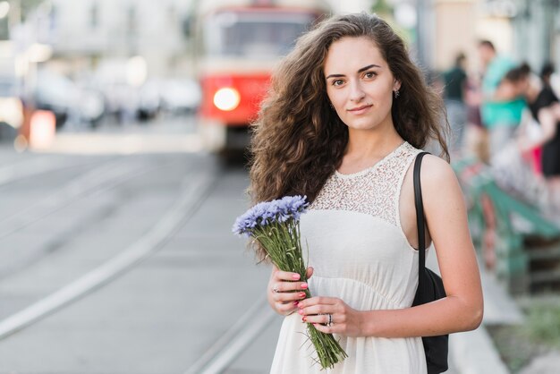 Hermosa mujer con flores en la calle