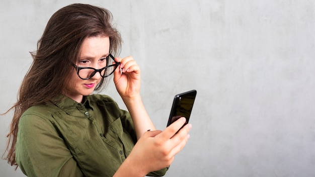 Hermosa mujer con gafas revisando su teléfono