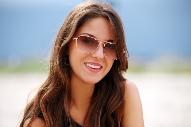 Hermosa mujer con gafas de sol en la playa