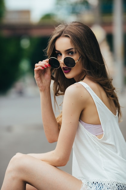 Foto gratuita hermosa mujer con gafas de sol sentada en el asfalto