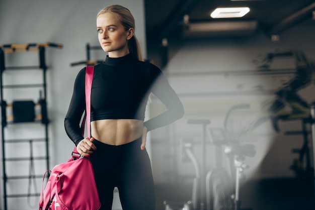 Hermosa mujer en el gimnasio con bolsa rosa.