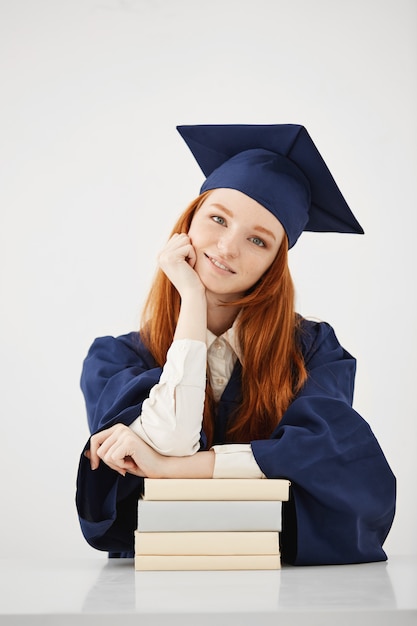 Hermosa mujer graduada con libros sonriendo.