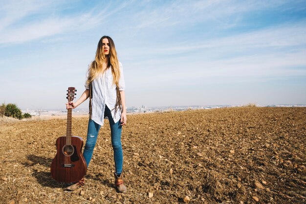 Hermosa mujer con guitarra en la naturaleza