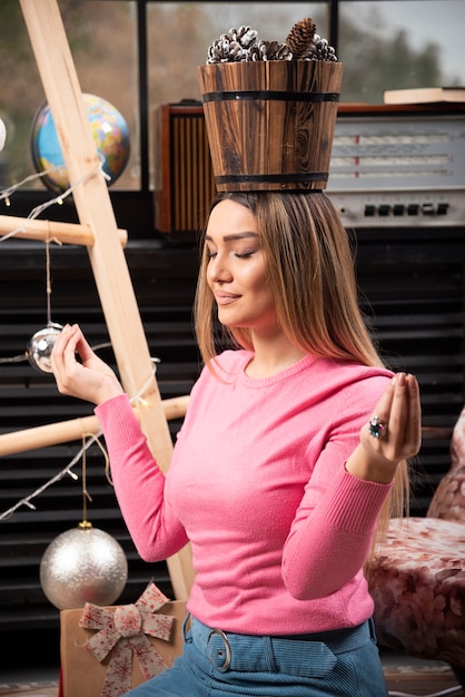 Hermosa mujer haciendo meditación con cubo de piñas.