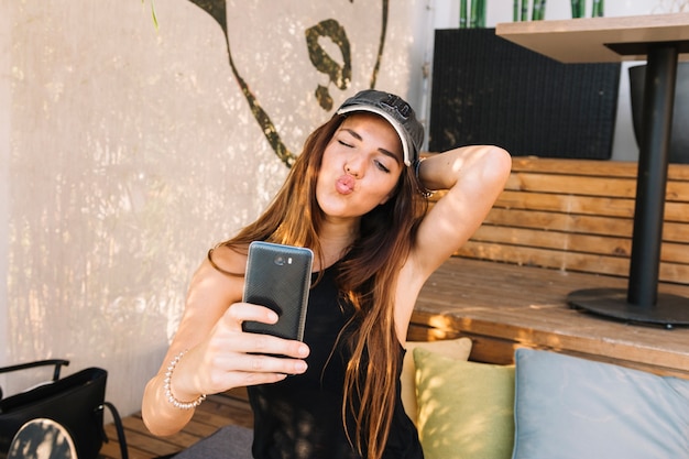 Foto gratuita hermosa mujer haciendo pucheros mientras toma selfie en celular