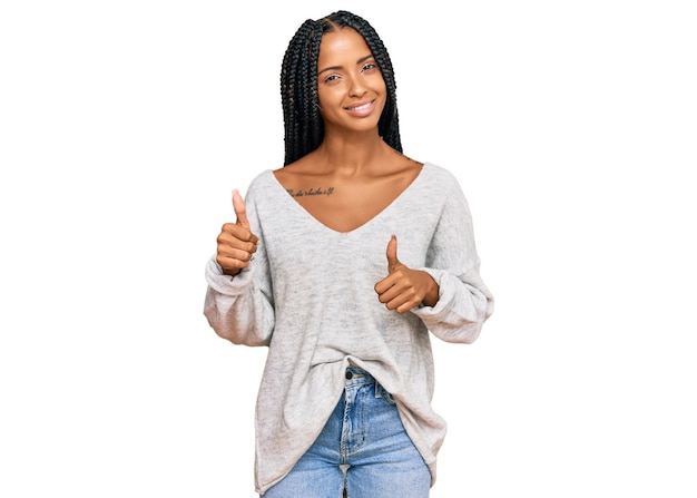 Hermosa mujer hispana con ropa informal signo de éxito haciendo un gesto positivo con la mano, pulgares arriba sonriendo y feliz. expresión alegre y gesto ganador.