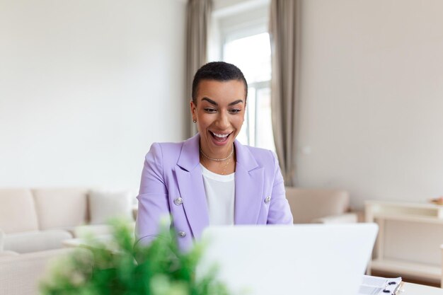 Hermosa mujer independiente anotando información para planificar un proyecto haciendo un trabajo remoto a través de una computadora portátil mujer riéndose mientras lee el correo electrónico en un dispositivo portátil moderno