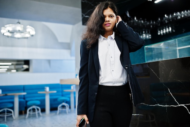 Hermosa mujer india usa una pose formal en el café cerca del mostrador del bar