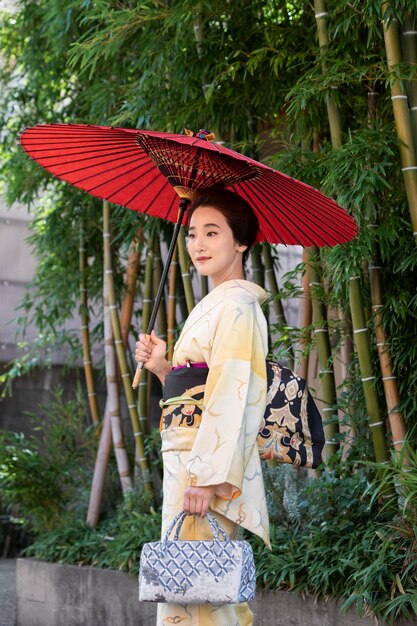 Foto gratuita hermosa mujer japonesa con una sombrilla roja al aire libre