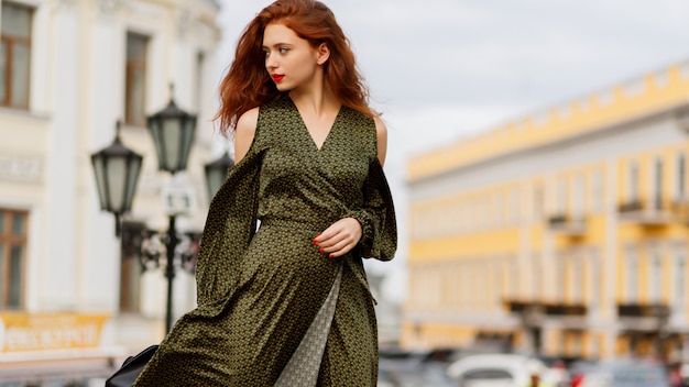 Hermosa mujer de jengibre rizado con labios rojos posando al aire libre en un cálido día de primavera.