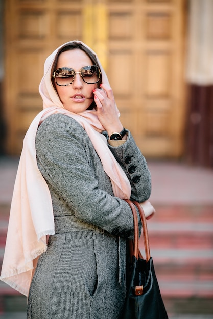 Foto gratuita hermosa mujer joven en un abrigo con una bolsa posando