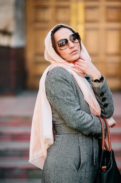 Foto gratuita hermosa mujer joven en un abrigo con una bolsa posando