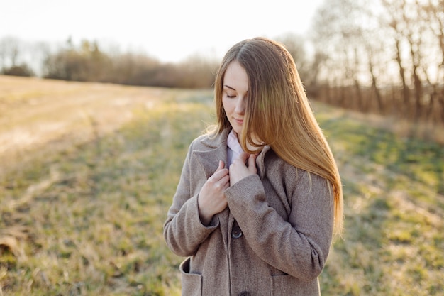 Hermosa mujer joven en abrigo de lana en el bosque al atardecer