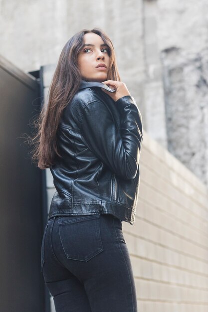 Hermosa mujer joven ajustando su chaqueta de cuello de cuero